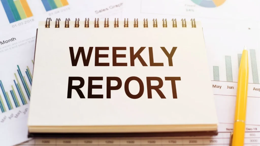 Spiral notepad labelled "Weekly Report" resting on printed sales graphs and bar charts, representing a VA weekly report template for tracking tasks and progress.