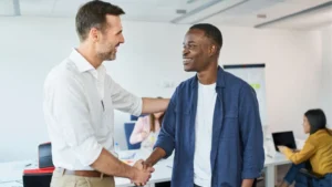 Business owner shaking hands with a new virtual assistant during onboarding in a modern office